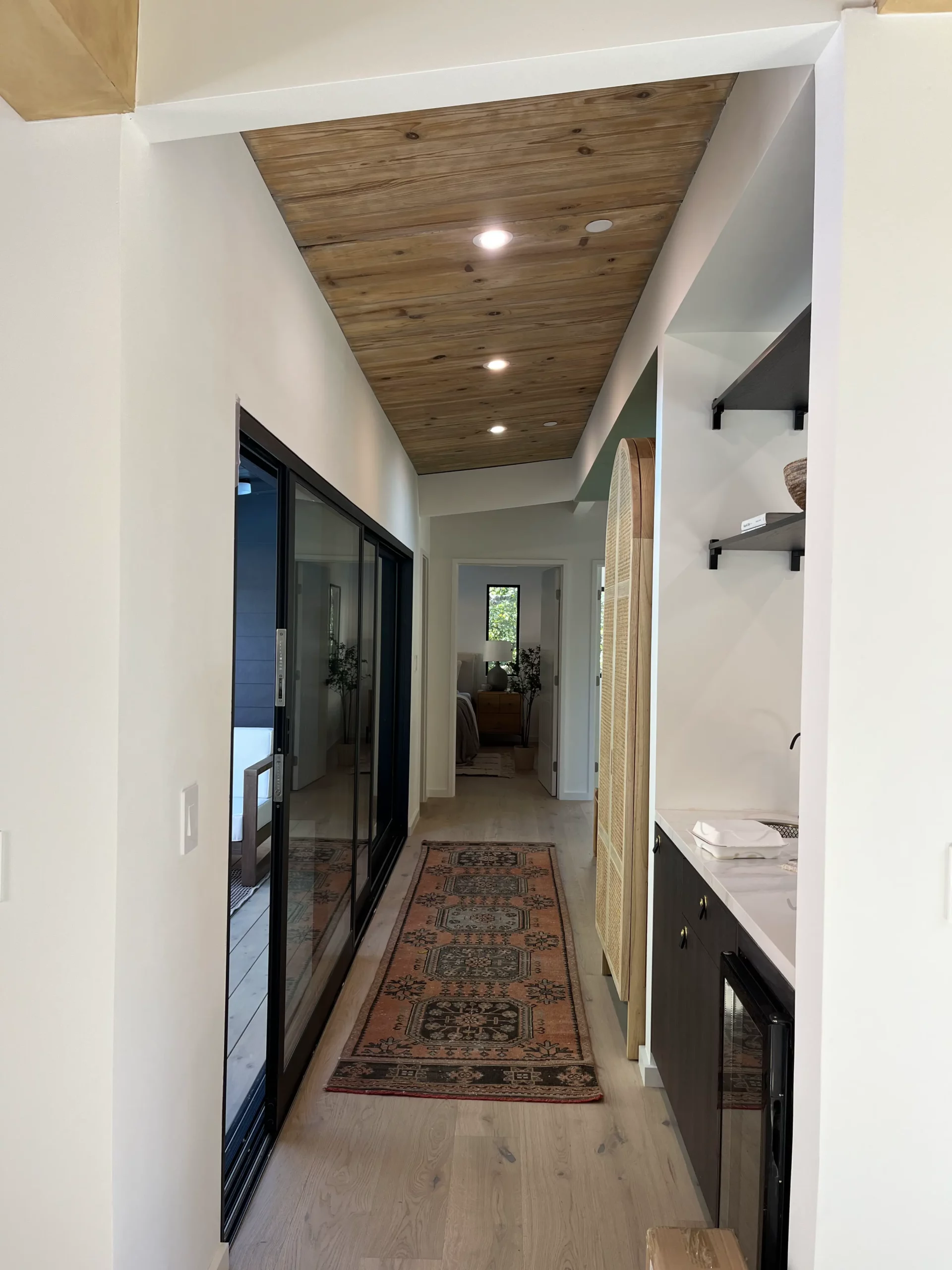 A hallway with a wooden ceiling and a rug.