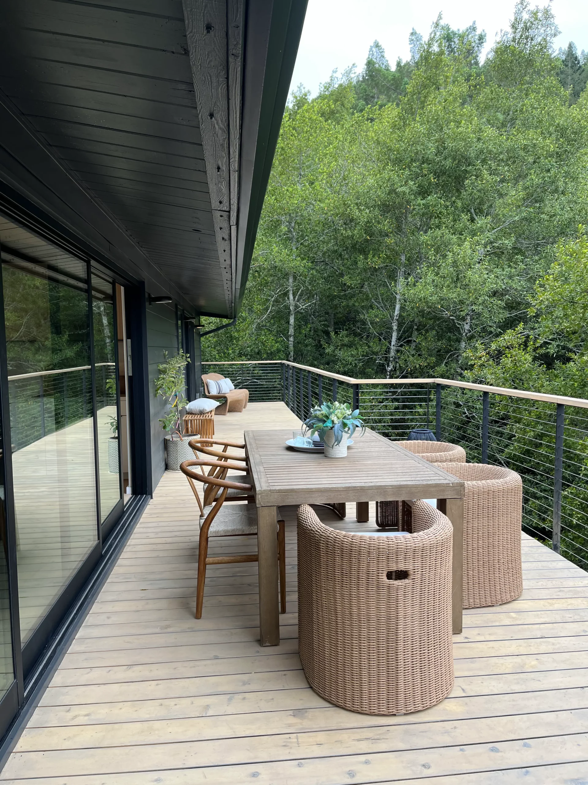 A deck with a table and chairs overlooking a wooded area.