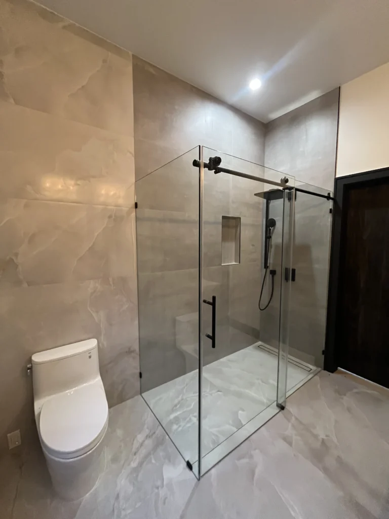 A bathroom with a glass shower stall and toilet.